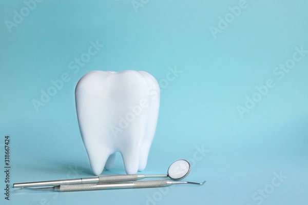 Fototapeta White tooth with dental instruments on a blue background in honor of the international day of the dentist on February 9