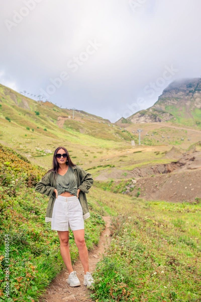 Fototapeta Beautiful happy young woman in mountains in the background of fog