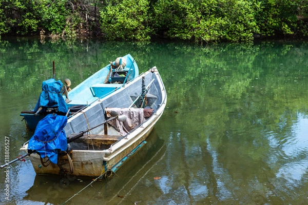 Fototapeta Old metal fishing boat floating on the river with green tree at the background, transportation concept, travel by boat, outdoor day light