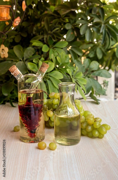 Fototapeta Bottles of wine and a bunch of grapes on a table close-up