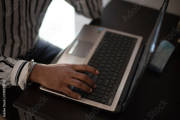 Obraz Top view of hand gesture of corporate employee doing work in laptop on his desk in Indian office. Indian corporate.