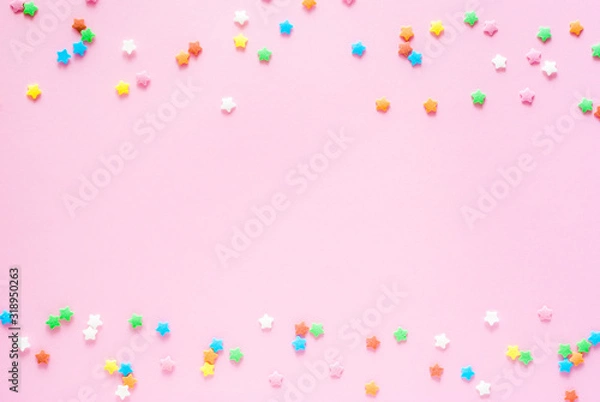 Fototapeta Colored sugar stars sprinkled on a pastel light pink backdrop. Background composition with copy space, top view