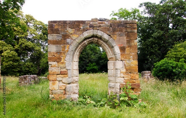 Obraz Ruined stone archway in grassy field