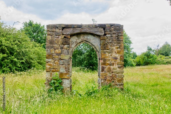 Obraz Ruined stone archway in grassy field