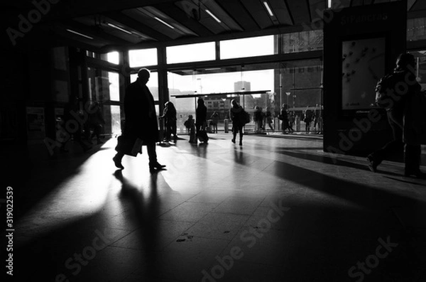 Fototapeta Silhouette of a man carrying a portfolio that runs through a light window of a train station