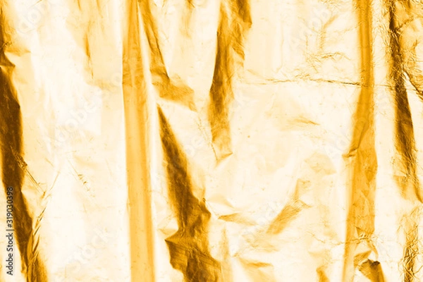 Obraz Gold texture, gold-plated surface made of crumpled fabric. Thin metal foil sheet, iron with cracks and irregularities. Crumpled, textured paper for decoration and design with a gold reflective layer.