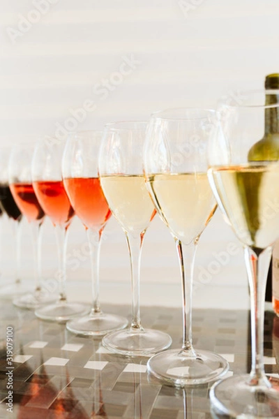 Fototapeta Wine tasting set in the light airy environment. Custom wine tasting concept. Glasses of wine and bottles on the glass table and light background.