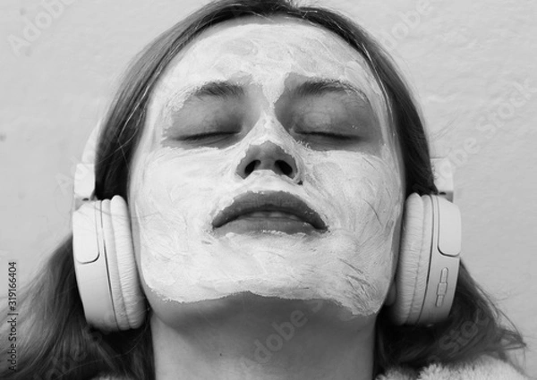 Obraz Portrait of young woman with a mask on the face listening to music