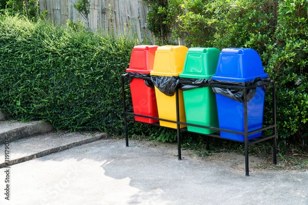 Fototapeta Various colorful rubbish bin or trash can in the garden background. Row of multicolor plastic litter bin in public park beside the street and staircase