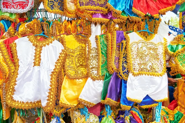 Fototapeta Colorful festive handmade dresses for children are sold in honor of Santo Nino at a stand at the Ati-Atihan Festival in Ibajay, Philippines 