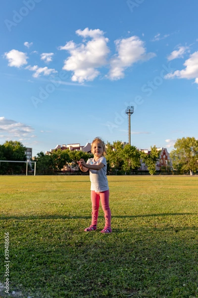 Fototapeta A small child goes in for sports in the stadium. hanging on the horizontal bar, on the uneven bars