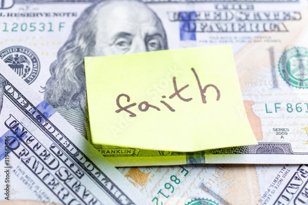 Obraz Yellow stick note on an USD money background. The inscription "faith" on a yellow memory sticky note. Close up