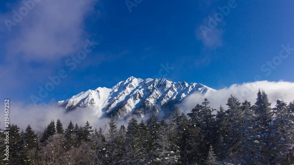 Fototapeta Japan Aleps mountains in winter cover with snow and blue sky during travel in Shinhotaka ropeway, Japan