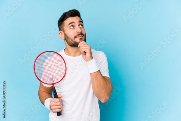 Fototapeta Young handsome man playing badminton isolated looking sideways with doubtful and skeptical expression.