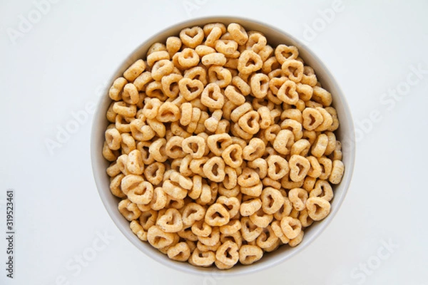 Fototapeta Bowl of whole grain oat cereal on a white background, top view. Heart shapes cereal. 