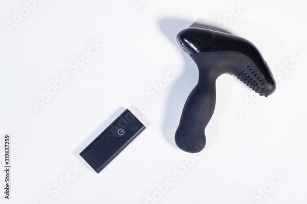 Fototapeta Mechanical vibrating  anal plug with a remote control on a white background, top view. Sex game. Prostate massage.