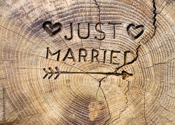 Fototapeta Just married. An inscription on a cut of a tree for a wedding decoration. Handmade decorative board on oak. Photo for your invitation design.