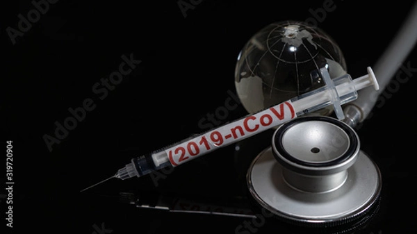 Fototapeta Syringe have text "(2019-nCoV)" and globe model and stethoscope  put on  Black background. corona virus Concept.