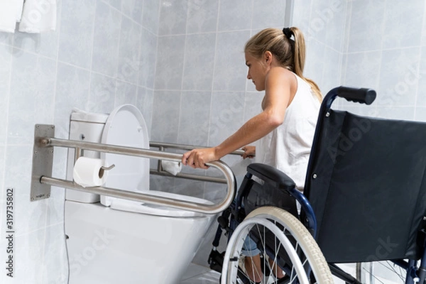 Fototapeta Blonde girl holding on to rails at the toilet trying to get up