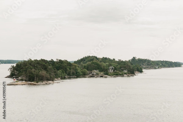 Fototapeta A huge green rocky peninsula with a forest and a village in the afternoon