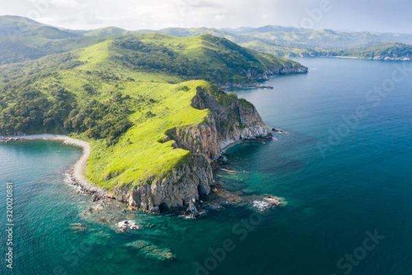 Fototapeta Aerial view of green rocky coastline and clean turquoise sea in Asia.  Cape Azaryev at Gamov Peninsula in summertime. Seaside nature landscape in Primorsky Krai, Far East, Russia