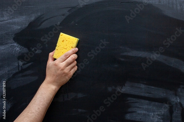 Obraz Erasing the Chalkboard. hand wipes the chalk from the chalkboard