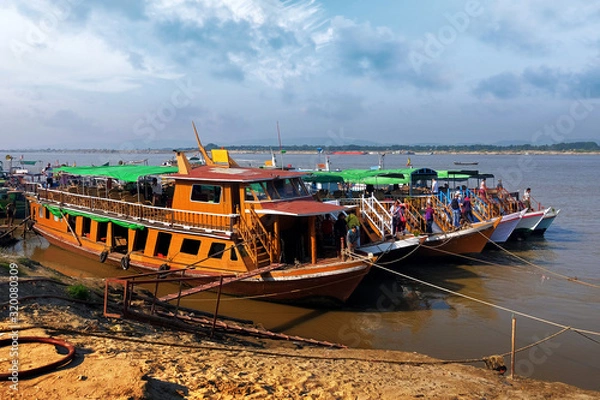 Fototapeta Traditional colorful Burmese boats on the Irrawaddy River, in the port of Mandalay, Myanmar, against a clear blue sky.