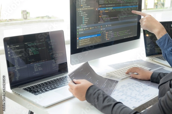 Obraz Programmers work on the development of coding and coding technology on white desks and website design, software, data processing companies, servers.