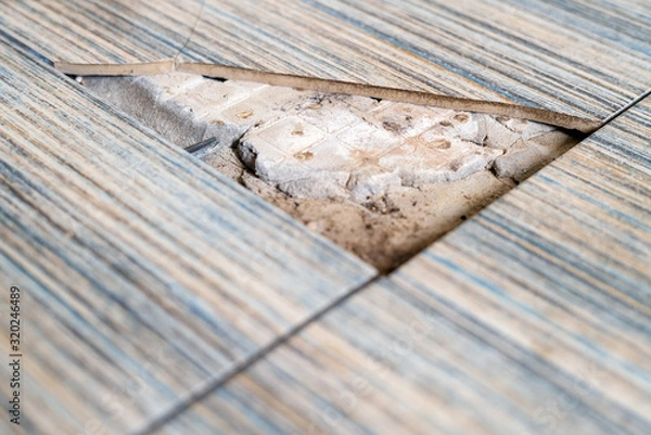 Fototapeta Close up view of broken tile in the bathroom. Cracked asbeston floor tile. Damaged ceramic tile background