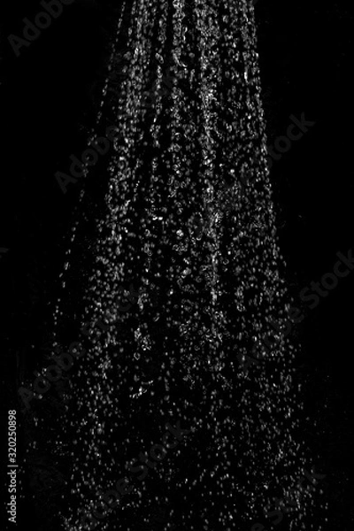 Fototapeta Blurred background with a stream of water splashing out of the shower against a dark background. Image to use as an element or background mock up