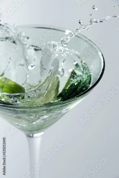 Obraz Splash from limes in a glass of cocktail, On the white background