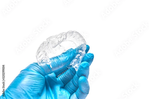 Fototapeta Hand is holding set of custom dental trays for bleaching teeth. Isolated on a white background