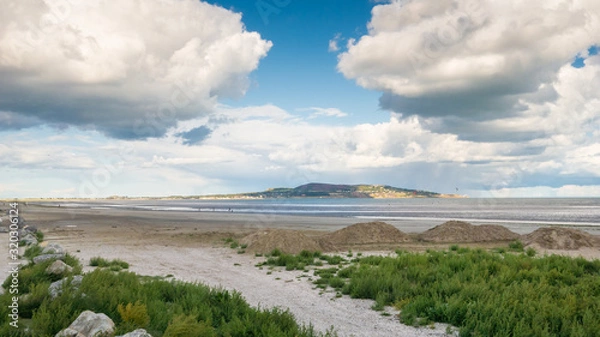 Obraz A view of spectacular white fluffy clouds at Dollymount Strand, County Dublin, Ireland. Howth Head peninsula can be seen in the distance.