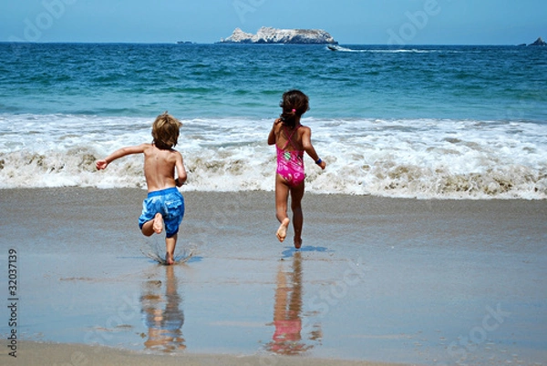 Fototapeta Boy and girl running on beach