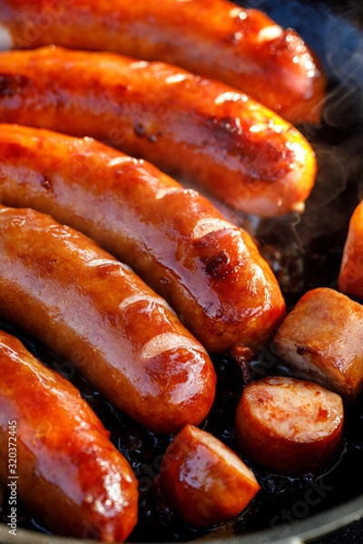 Obraz Fried pork sausages on a black background, close up view