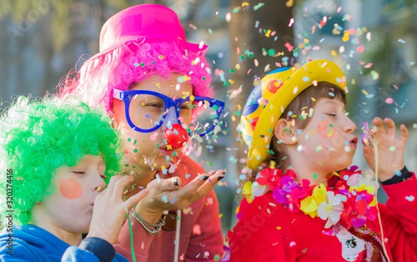 Obraz a mother and her children are playing with confetti in carnival costume