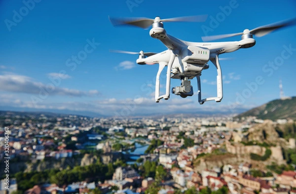 Obraz drone with digital camera hovering over city
