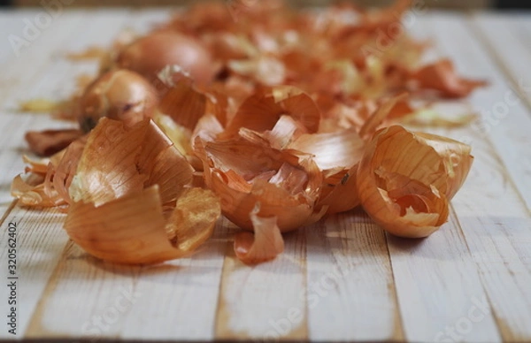 Fototapeta The use of onion skins in medicine and for coloring Easter eggs. Onion skin and onion on a wooden background.