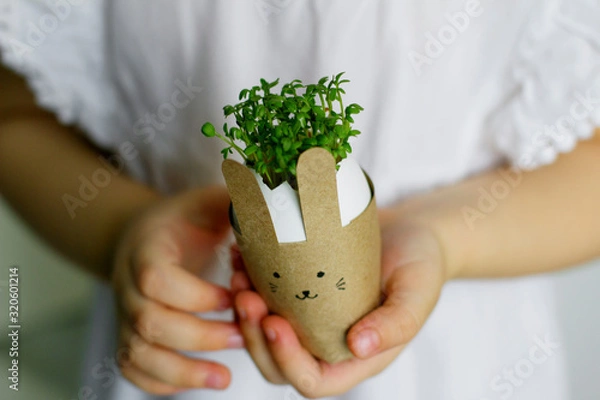 Obraz little girl holding an easter bunny with watercress in her hands