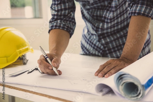 Fototapeta architect man handwriting with blueprint to build houses. After agreeing the employment price the cost of construction and repair real estate