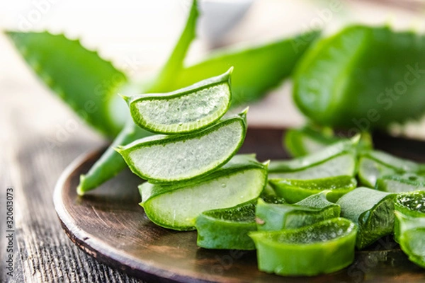 Fototapeta Slices of aloe vera in a bowl on a wooden table.