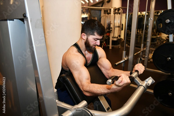 Fototapeta male athlete engaged in physical exercises in the gym