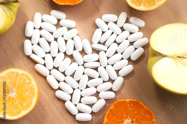 Fototapeta pills laid out in the shape of a heart on a background of fruits