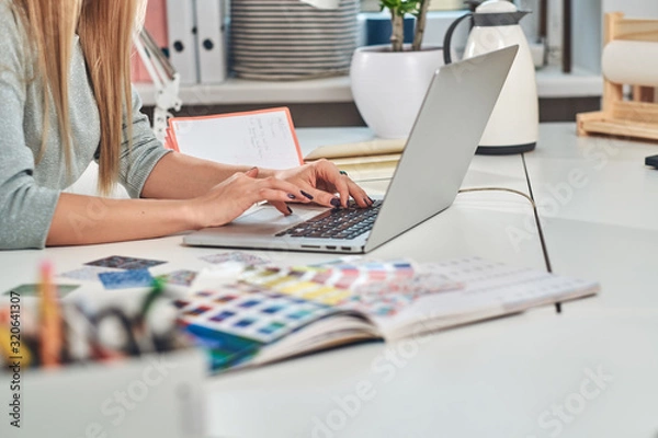 Fototapeta Woman with nice manicure is working on computer at creative studio.