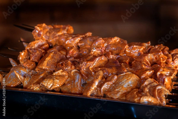 Fototapeta Close up of some meat skewers grilled in a barbecue. Barbecue grill, seasoned meat strung on skewers against the backdrop of the fire of a blazing fireplace in an expensive natural food restaurant