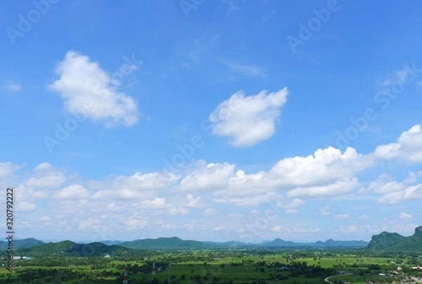 Obraz Green rice field with mountains under blue sky. The fields are grassy green.It's rainy season.Sky in the rainy season
