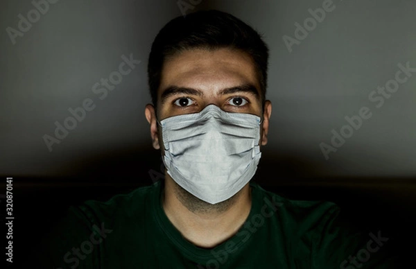 Fototapeta Portrait of a man in a surgical mask to protect against infections. Dark background