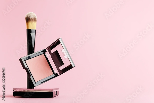 Fototapeta Composition with makeup items on a white background. Black brush, makeup tool, packing of rouge and powder levitate on a pastel backdrop. Set of beauty products for face, lips and eyes with copy space