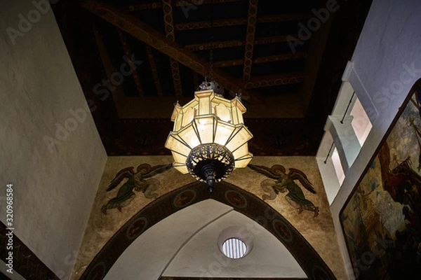 Obraz View of a chandelier hanging off the ceiling of the interior of a historical Spanish style building in California
