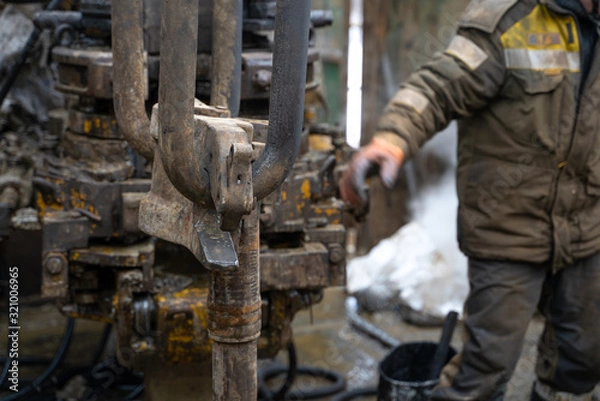 Obraz Offshore oil rig worker prepare tool and equipment for perforation oil and gas well at wellhead platform. Making up a drill pipe connection. A view for drill pipe connection from between the stands.